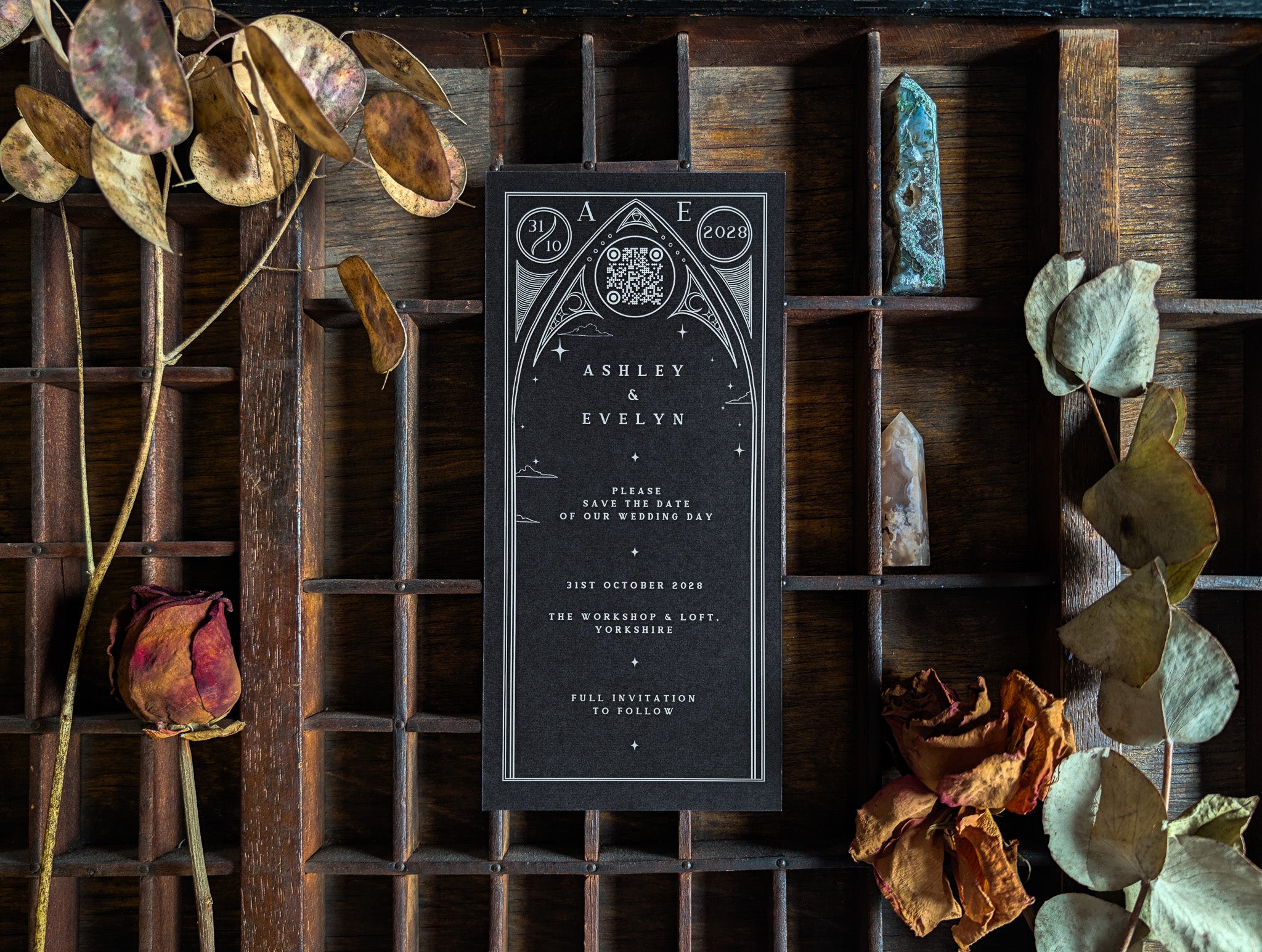 A gothic celestial save the date card from the sample pack, shown among dried flowers.