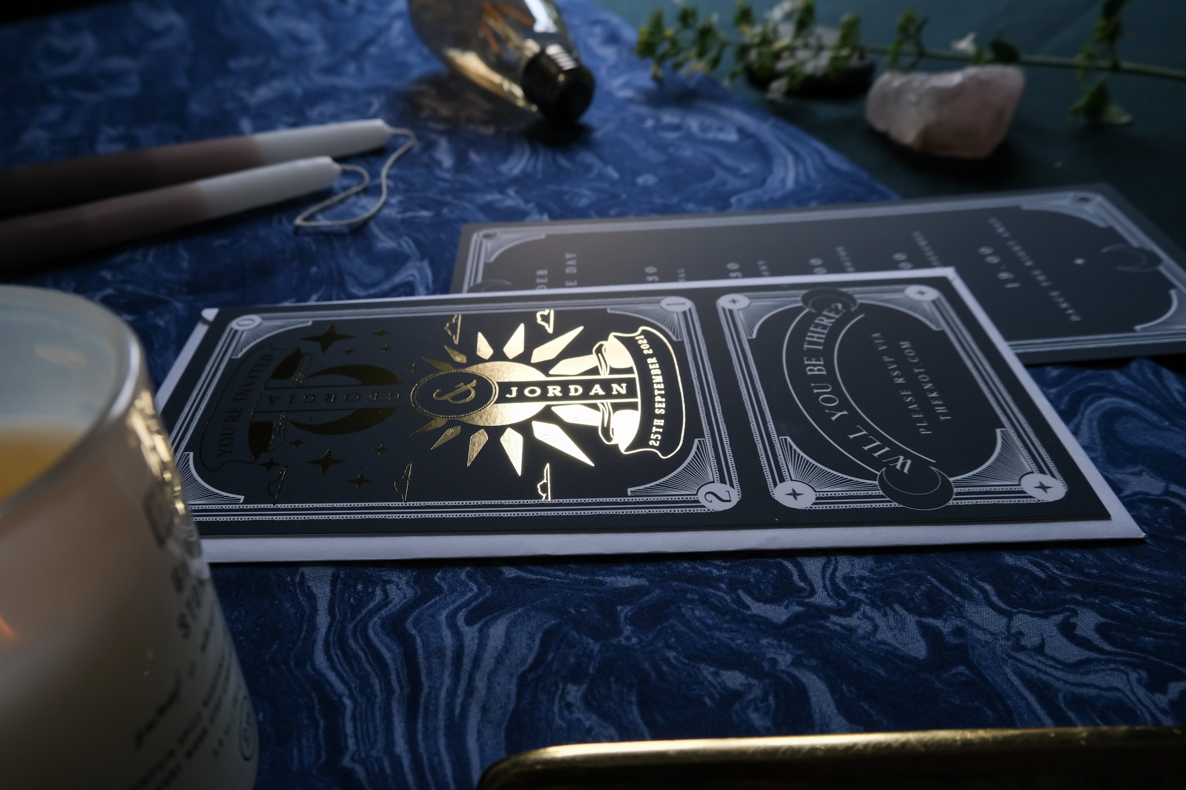 Premium UK celestial wedding stationery set with luxe foil and embossed sun, styled with quartz, candle, greenery; boho-romantic touch.