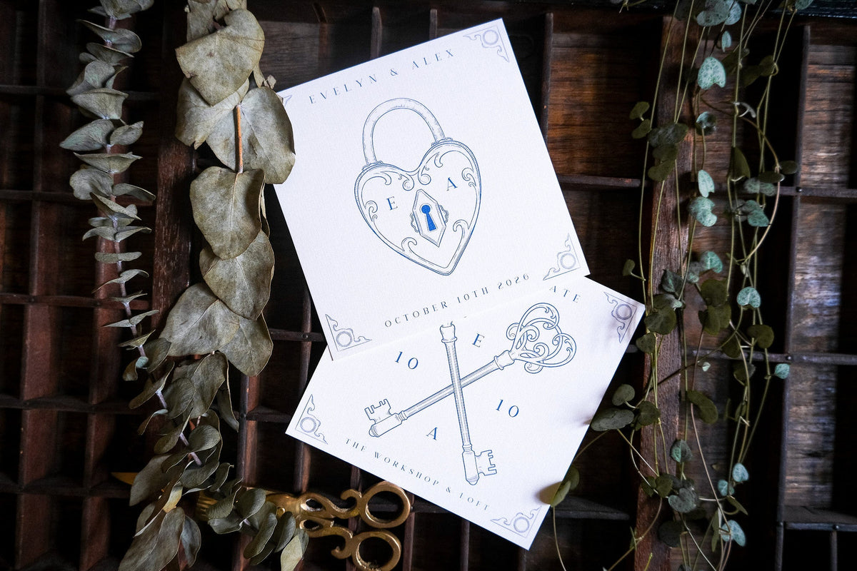 Luxury personalised wedding stationery with gothic crossed keys and heart padlock, on wood amid dried leaves for a romantic UK vibe.
