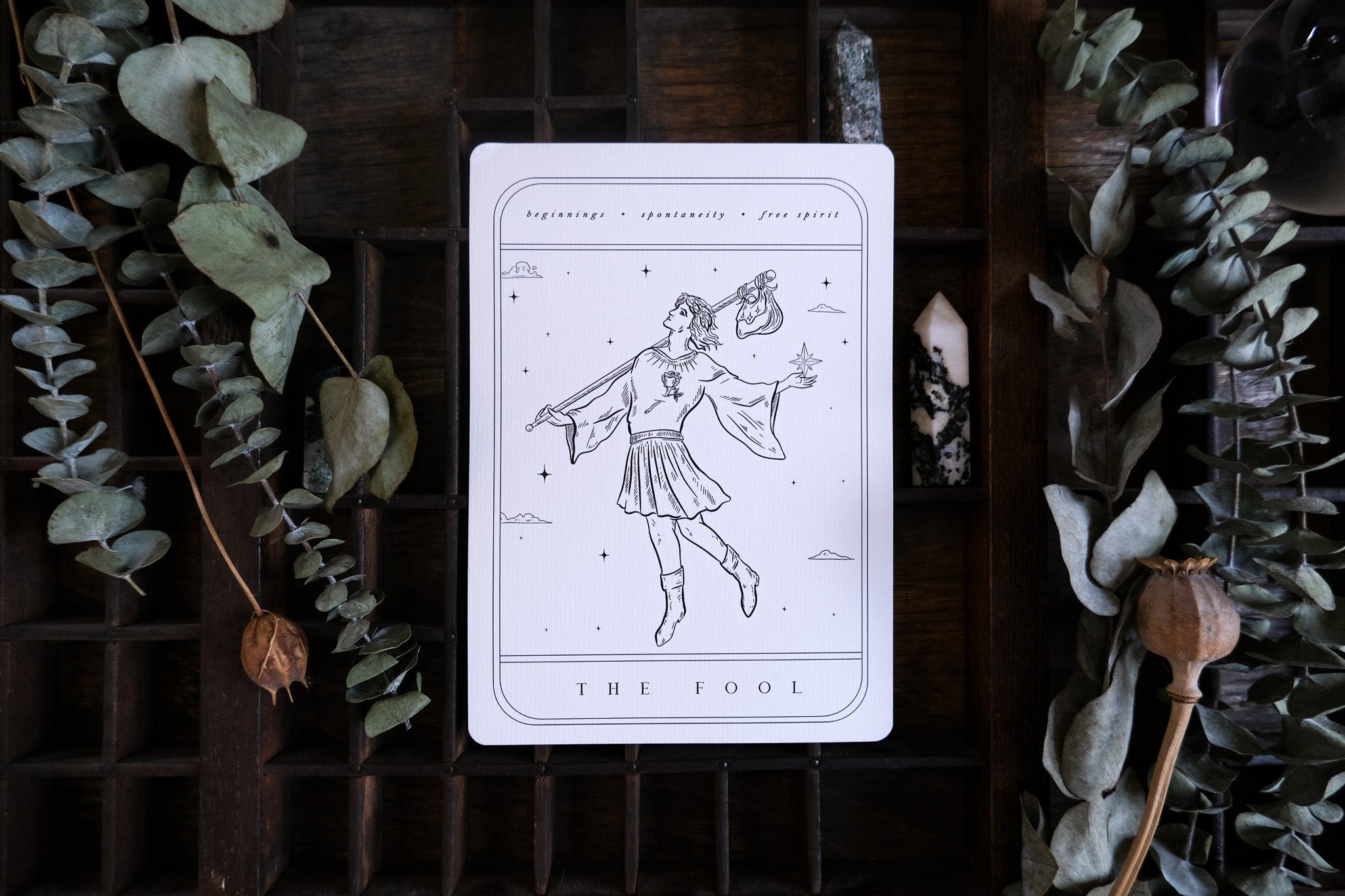 Luxury gothic wedding stationery art print, tarot-inspired, displayed on wood with dried leaves and crystals for a mystical touch.