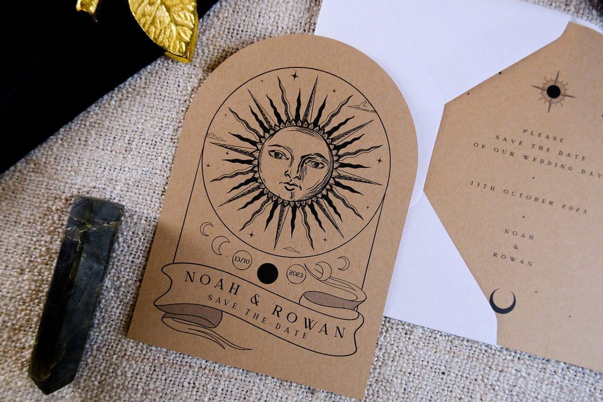 Luxury celestial wedding stationery featuring a kraft arched card with sun and moon, styled with a crystal on textured fabric.