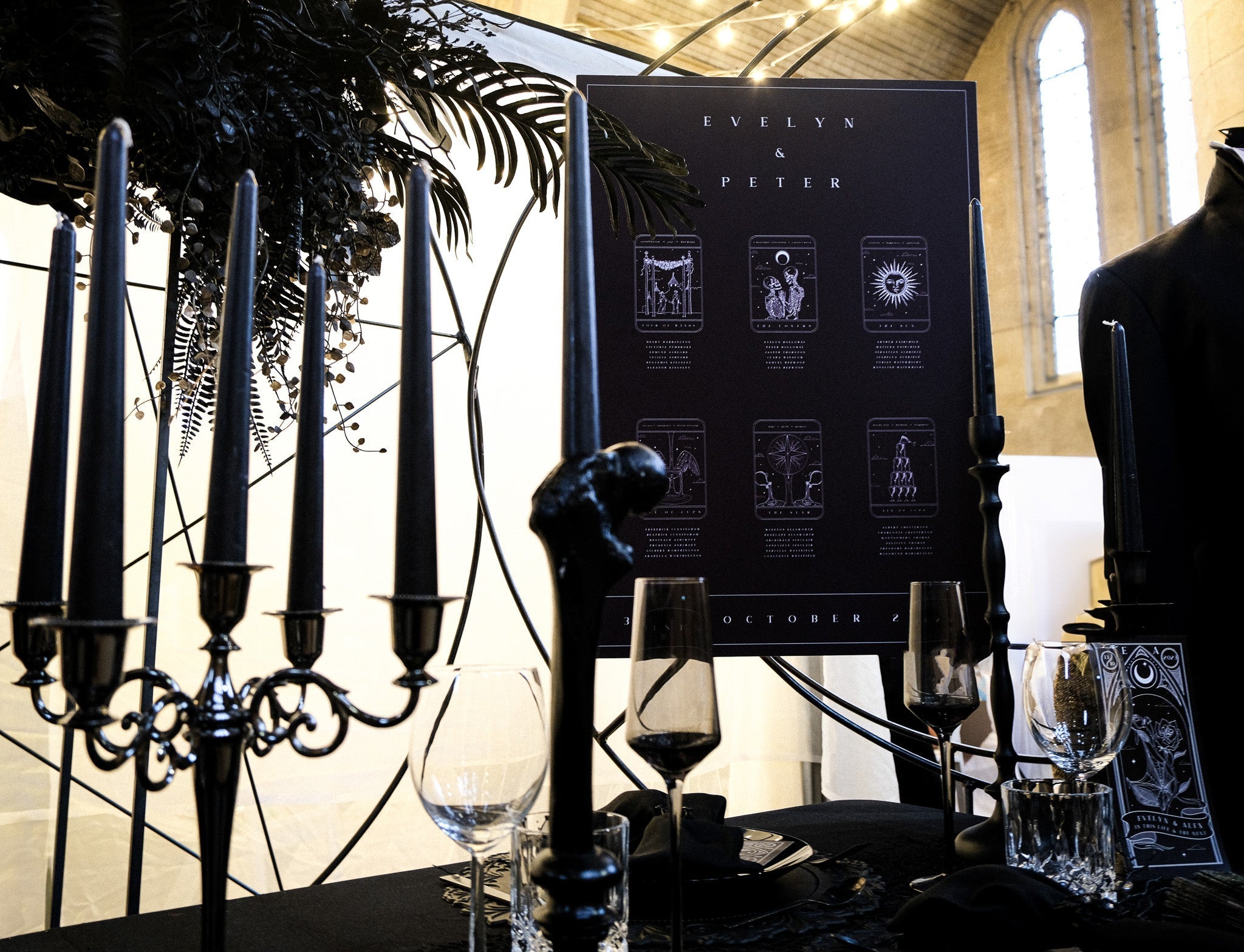 Luxury gothic wedding table featuring black candles, dark glassware, and a personalised tarot-inspired seating plan in a mystical setting.