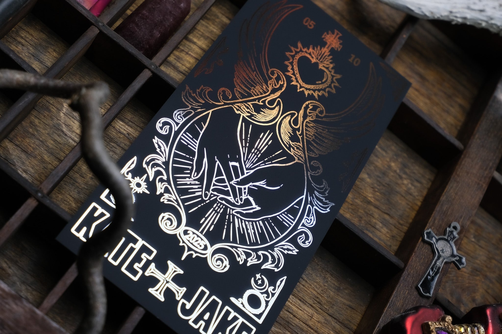Luxury UK wedding stationery Save the Date with gold foil, gothic art of two hands in a radiant heart, and dramatic black backdrop.