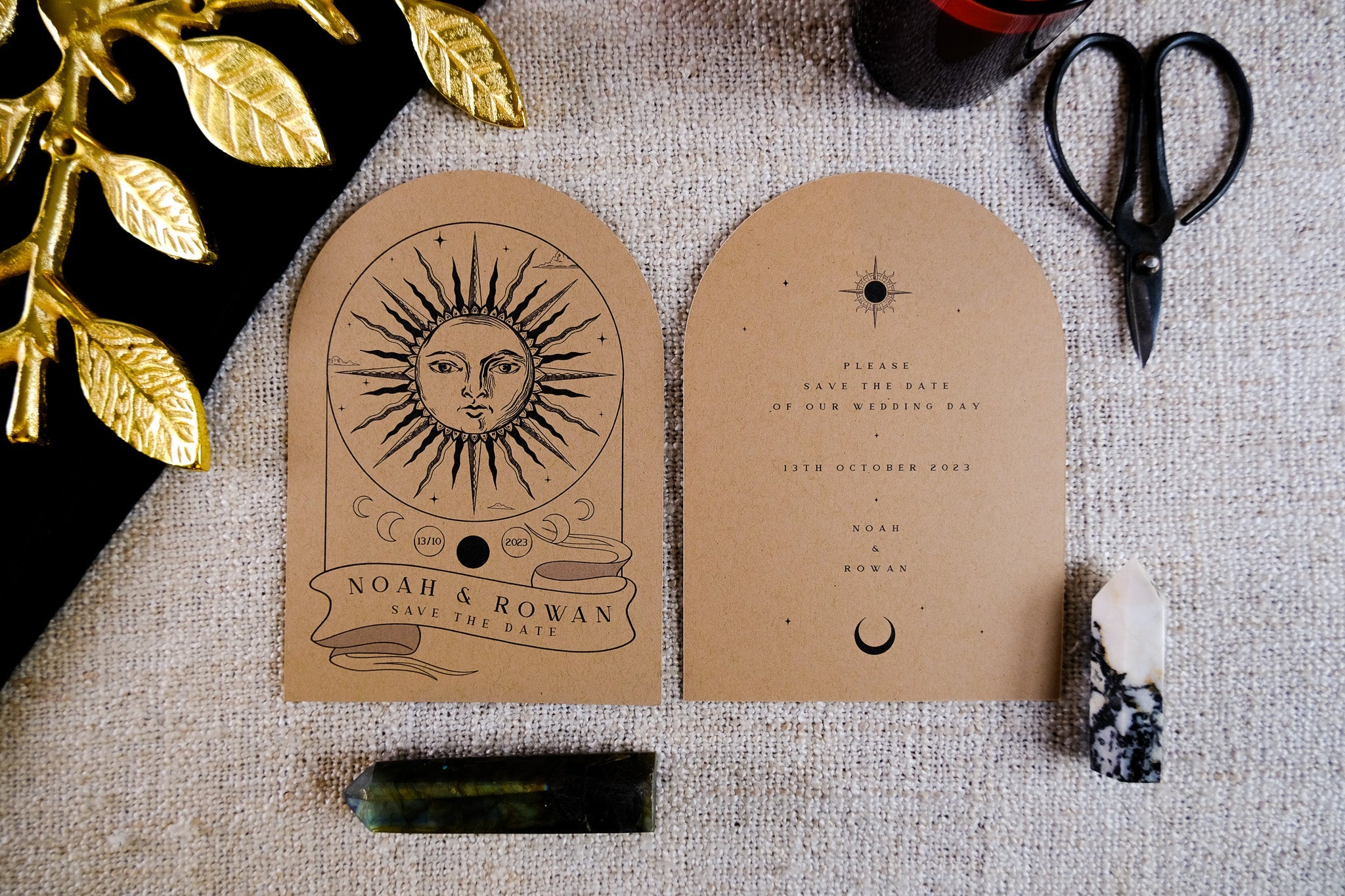 Luxury celestial wedding stationery featuring kraft brown arched cards with vintage boho designs, styled with stones and gold accents.