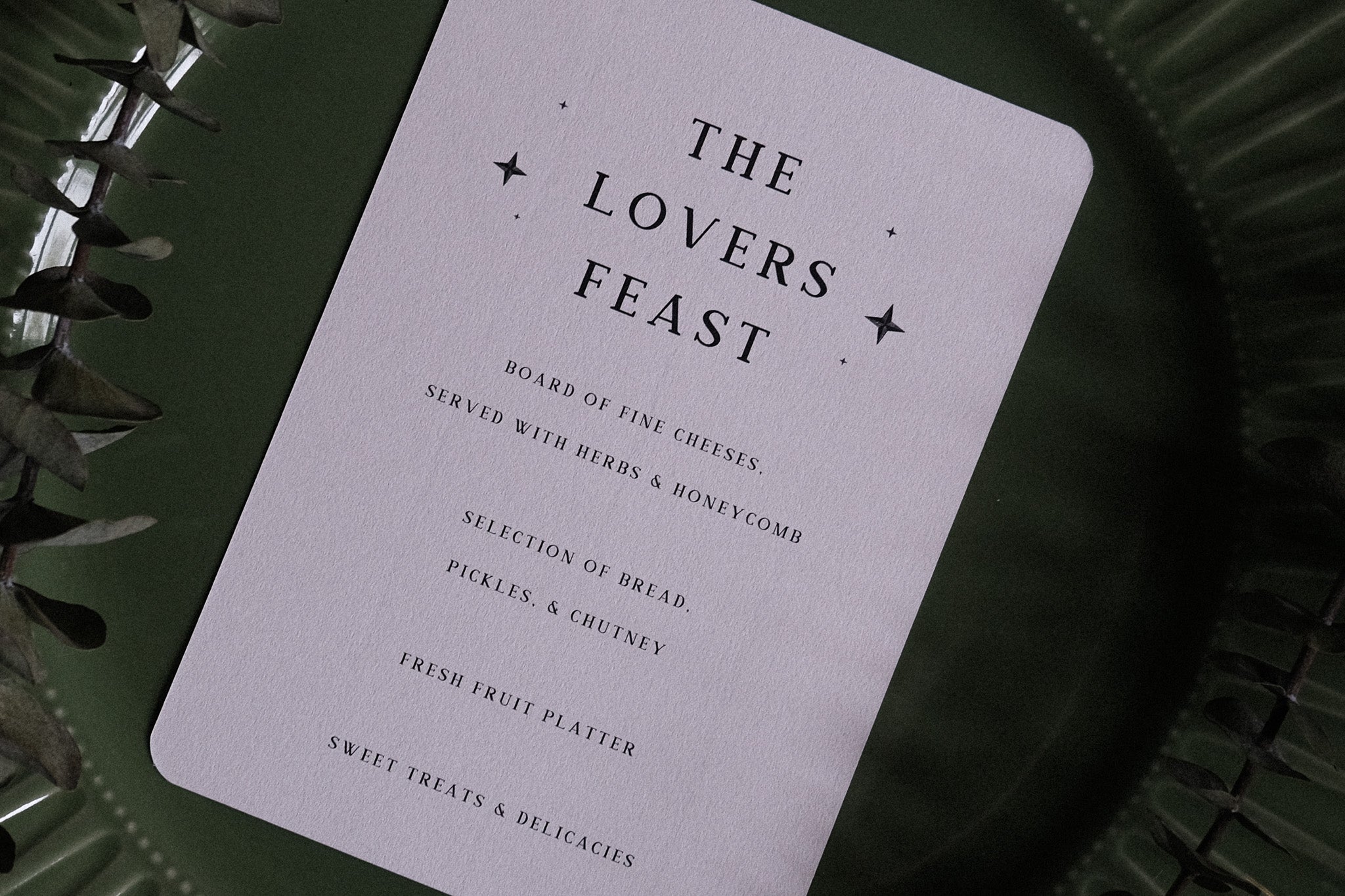 Luxury UK wedding menu with dramatic gothic artwork of a bleeding heart and crossed swords, styled atop a dark green plate.