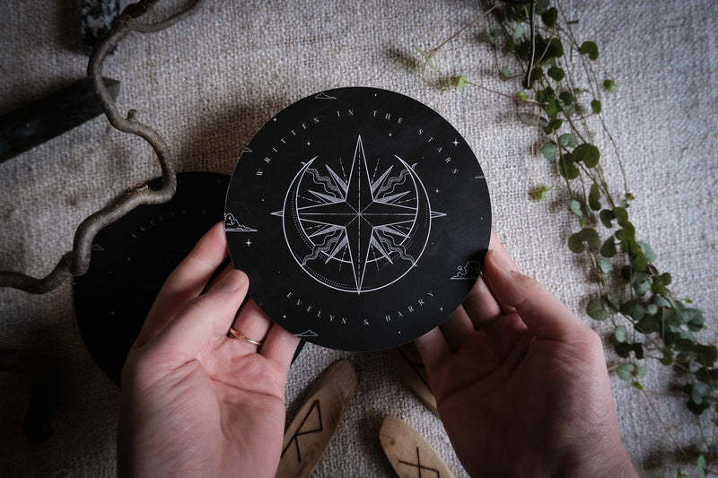 Luxury celestial circular save the date card with gothic compass, sun and moon design, rune accents and botanical details on textured paper.