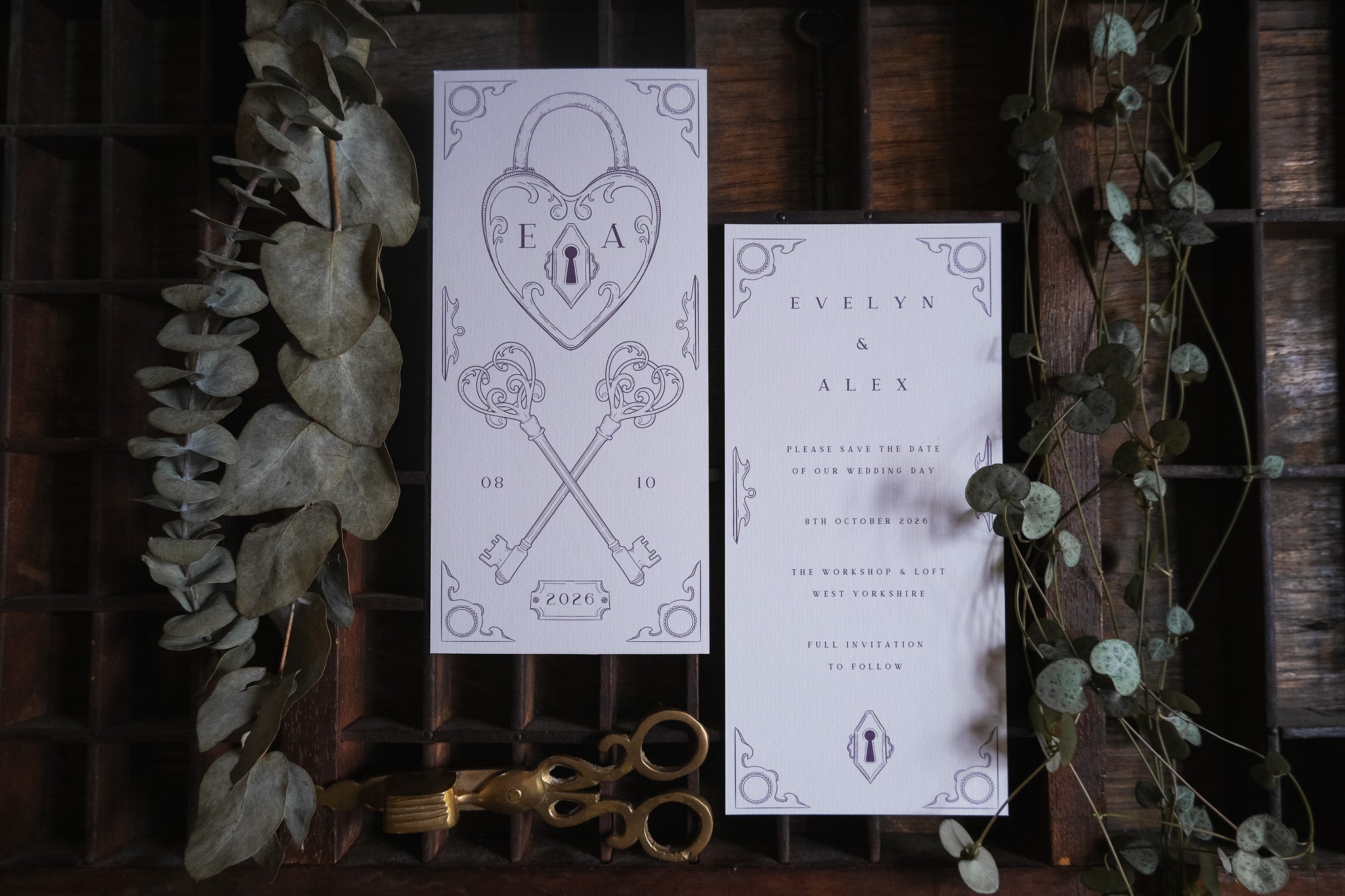 Luxury vintage Save the Date card with key and heart padlock motif, styled with dried eucalyptus and antique brass accents; UK wedding stationery.