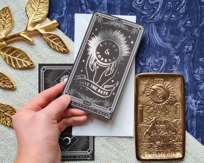 Hand holding a 'Crystal Ball' foiled tarot card save the date with mystical design elements.